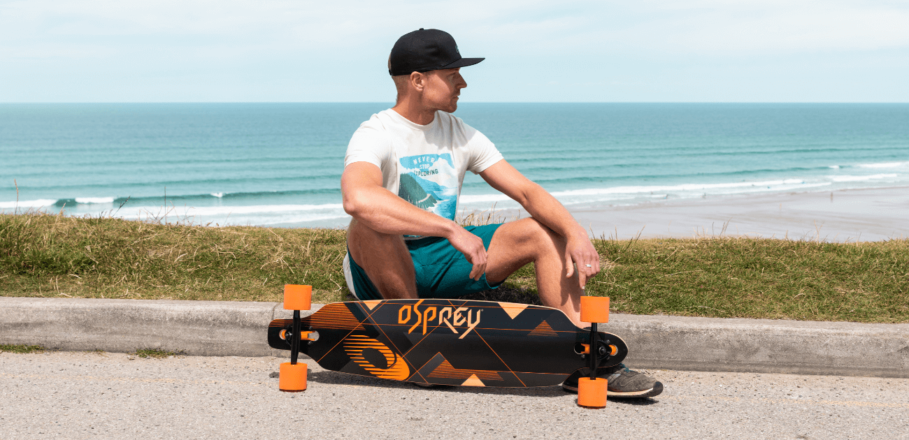 Man with a longboard, representing the excitement of getting started with skateboarding and beginner-friendly gear.