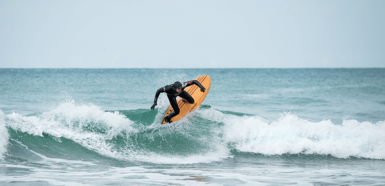 Male surfer catching a wave, illustrating how action sports like surfing can improve physical fitness and mental health.