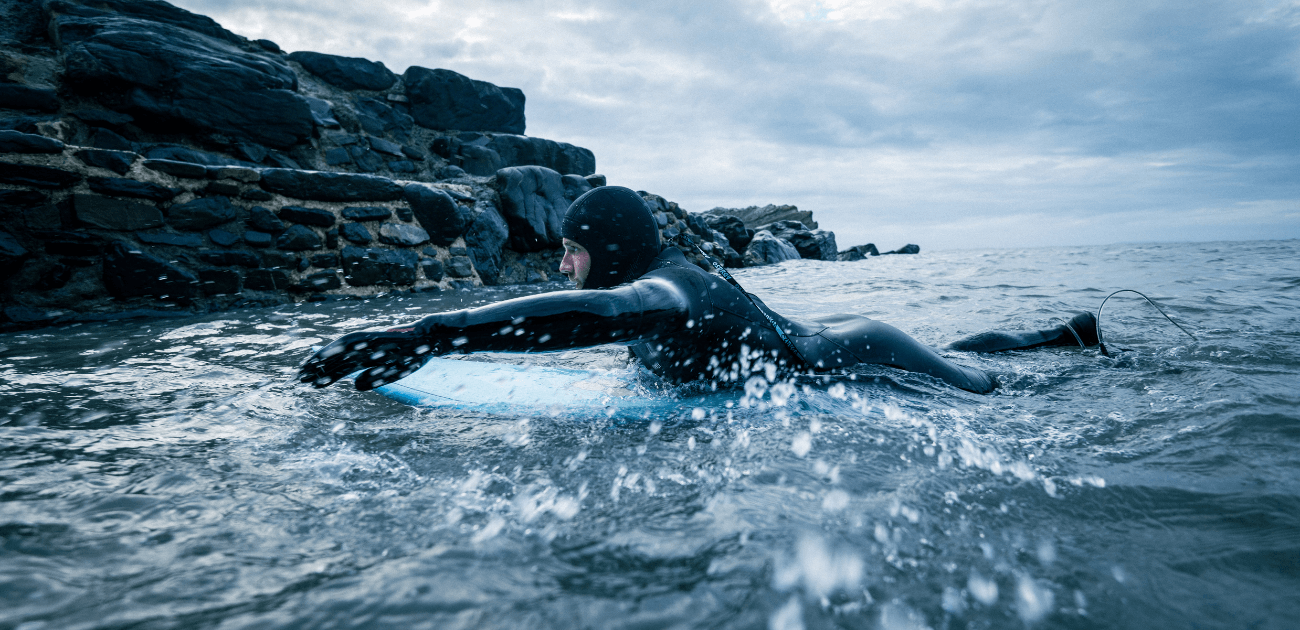 Surfer in cold water wearing Osprey hooded wetsuit, enjoying the benefits of cold-water surfing therapy