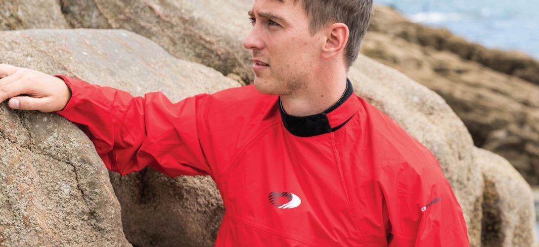 A photo of a man on the beach wearing a red Osprey spray jacket