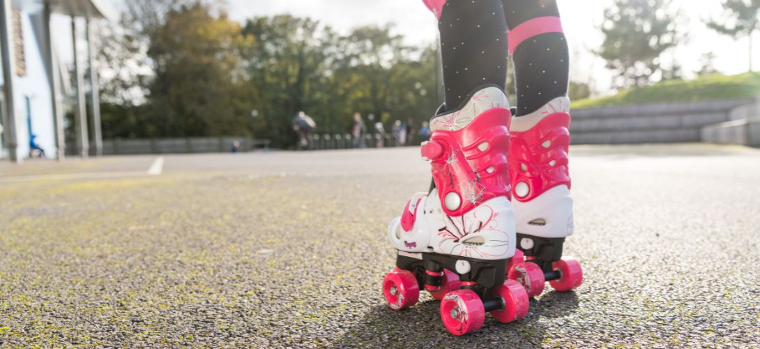 A close up image of a pair of kids pink and white Osprey quad skates