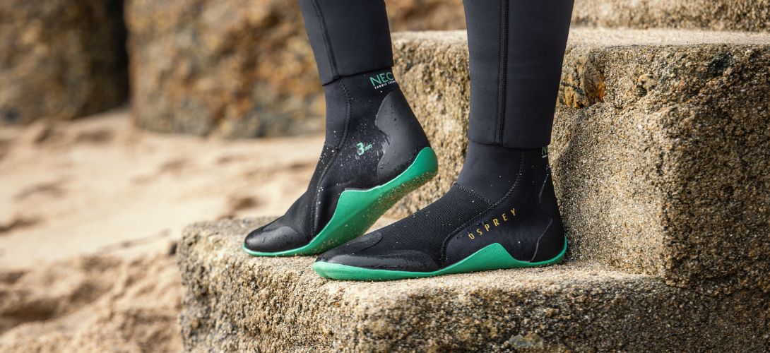 A pair of black Osprey Eco wetsuit boots with green soles