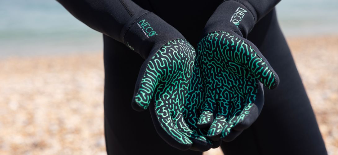a close up image of the palms of some wetsuit gloves. The palms have a green patterned grip
