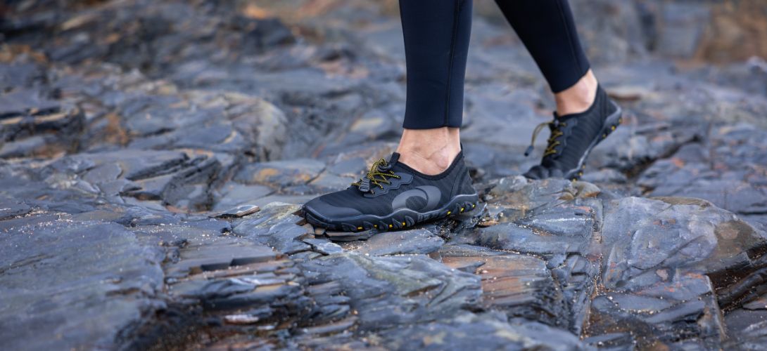 A close up photo of the Osprey water shoes being modelled by a woman on rocky terrain