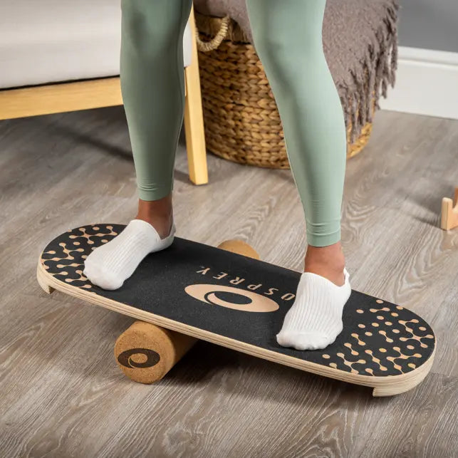 Person standing on a balance board in a home setting.