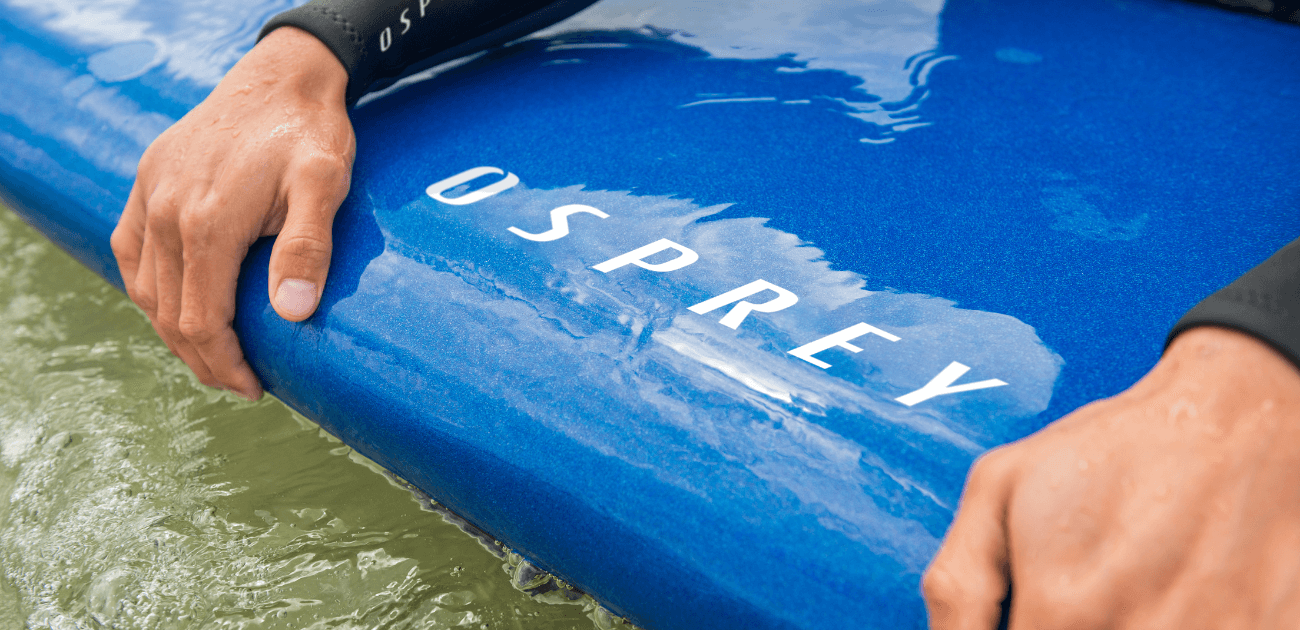 Close-up of surfer’s hands gripping an Osprey surfboard on Devon coastline, ready for UK surfing conditions