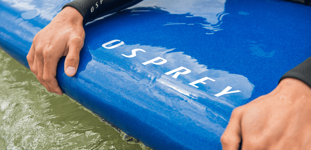 Close-up of surfer’s hands gripping an Osprey surfboard on Devon coastline, ready for UK surfing conditions