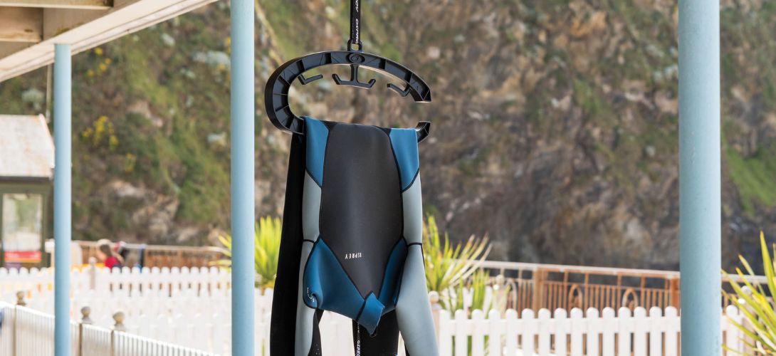 A photo of the Osprey wetsuit hanger with a mens blue and grey wetsuit hanging over it to dry