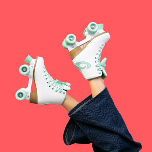 A model with their legs up in the air wearing  a pair of Osprey white retro quad roller-skates against a coral background