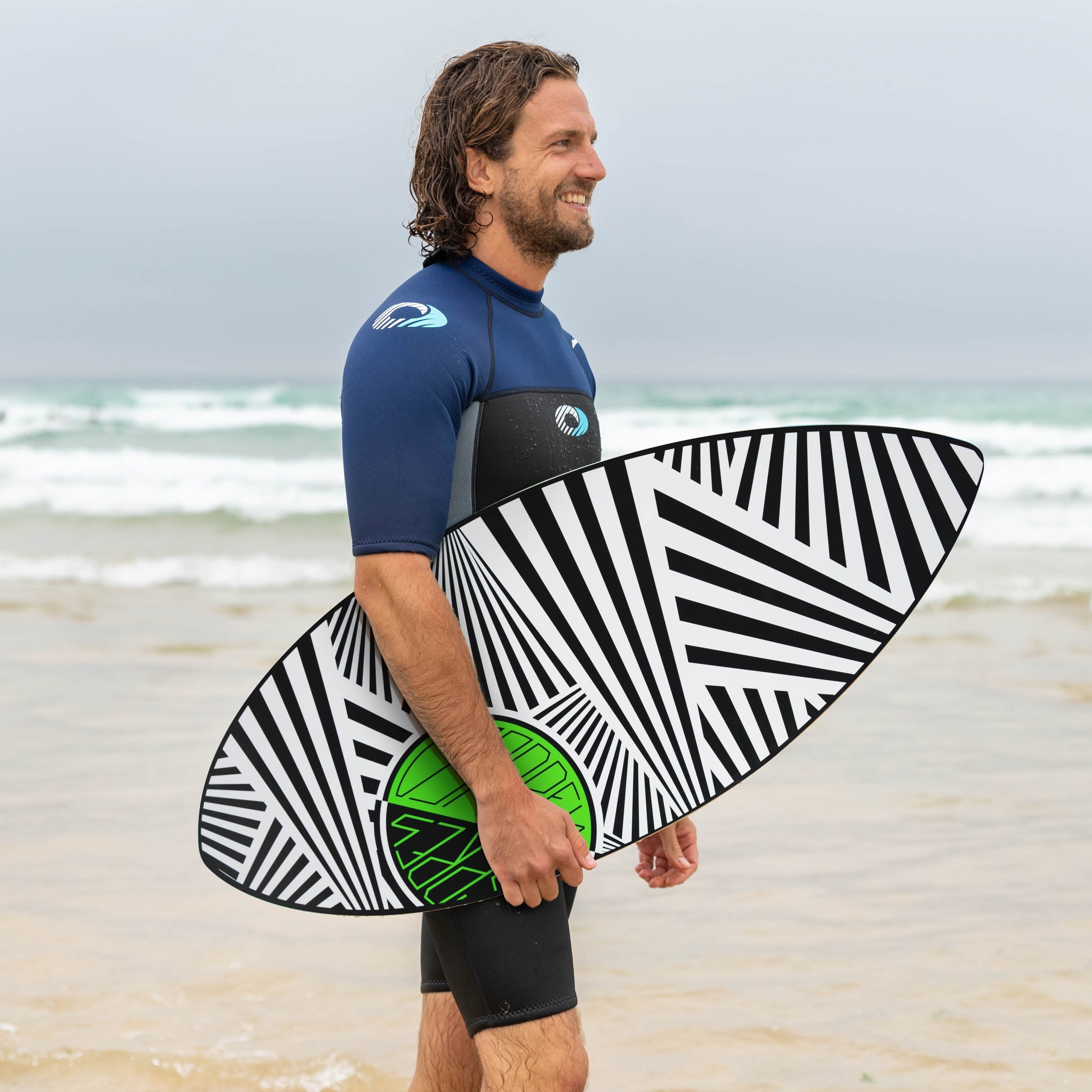 surfer holding the osprey skimboard on a uk beach with shallow waves